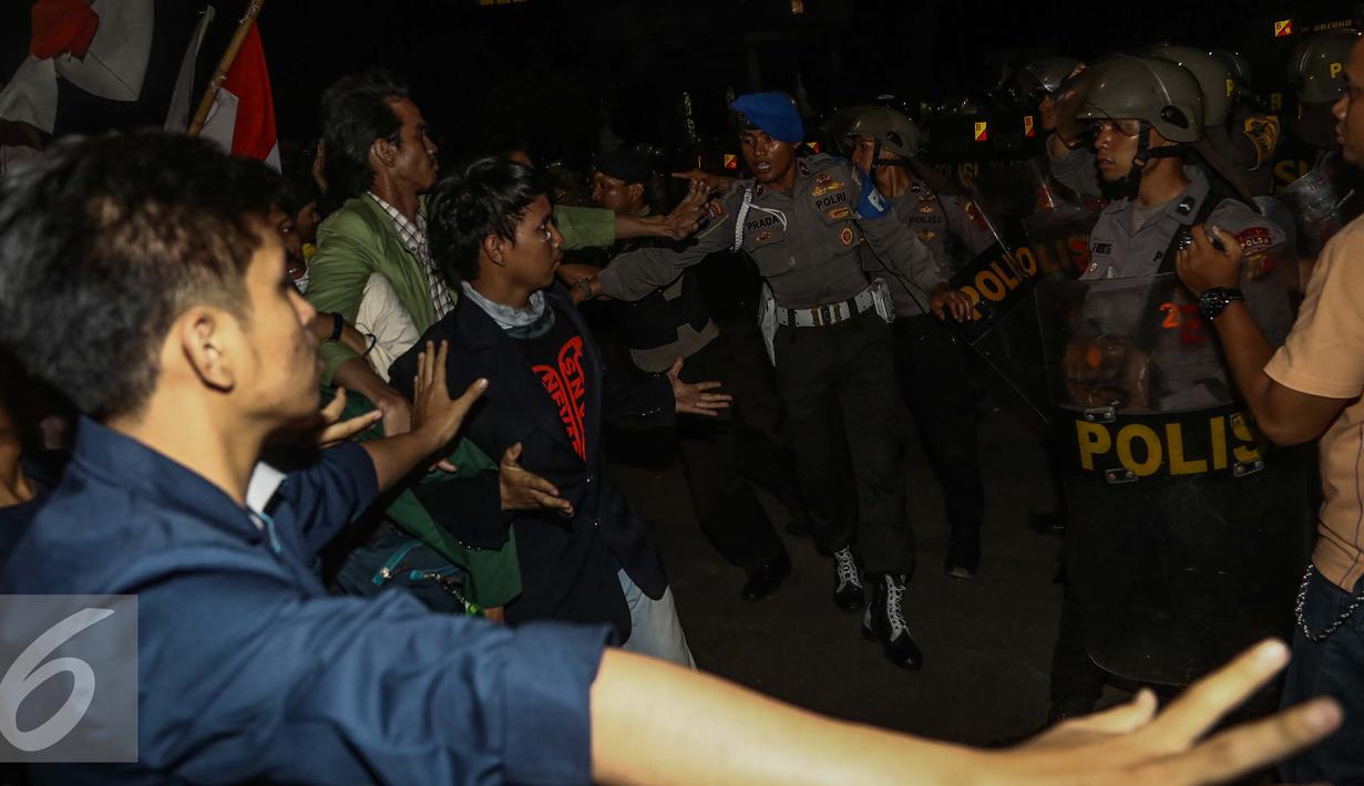 Massa aksi berhadapan dengan petugas polisi saat menggelar aksi unjuk rasa di depan Istana Negara, Kamis (12/1). Massa mahasiswa berkumpul di depan Istana di kawasan Jalan Merdeka Barat dengan membakar ban. (Liputan6.com/Faizal Fanani)