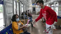 Petugas KAI Commuter (kanan) memberikan bunga dan healthy kit kepada perempuan pengguna KRL di Stasiun Jatinegara, Jakarta, Selasa (22/12/2020). Kegiatan tersebut dalam rangka memperingati Hari Ibu yang jatuh setiap tanggal 22 Desember. (Liputan6.com/Faizal Fanani)