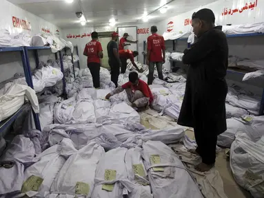 Relawan menempelkan kertas identifikasi pada setiap jenazah korban gelombang panas di sebuah kamar mayat di Karachi, Pakistan, Senin (22/6). Fenomena gelombang panas yang mendera Pakistan telah menewaskan setidaknya 122 orang. (REUTERS/Akhtar Soomro)