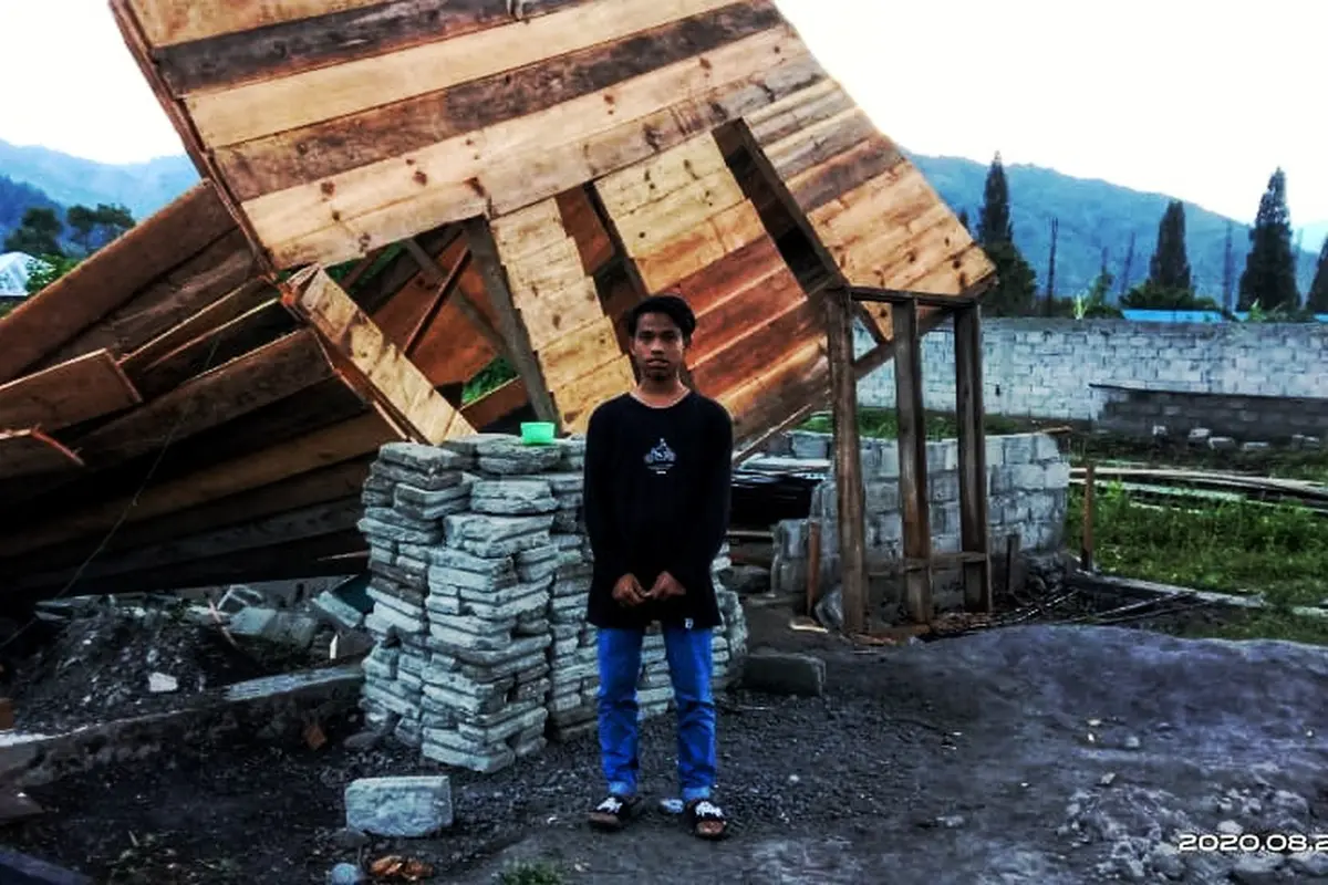 Seorang anak sedang berdiri di depan sebuah rumah yang roboh akibat terjangan angin puting beliung di Kecamatan Pegasing, Aceh Tengah (Liputan6.com/Ist)