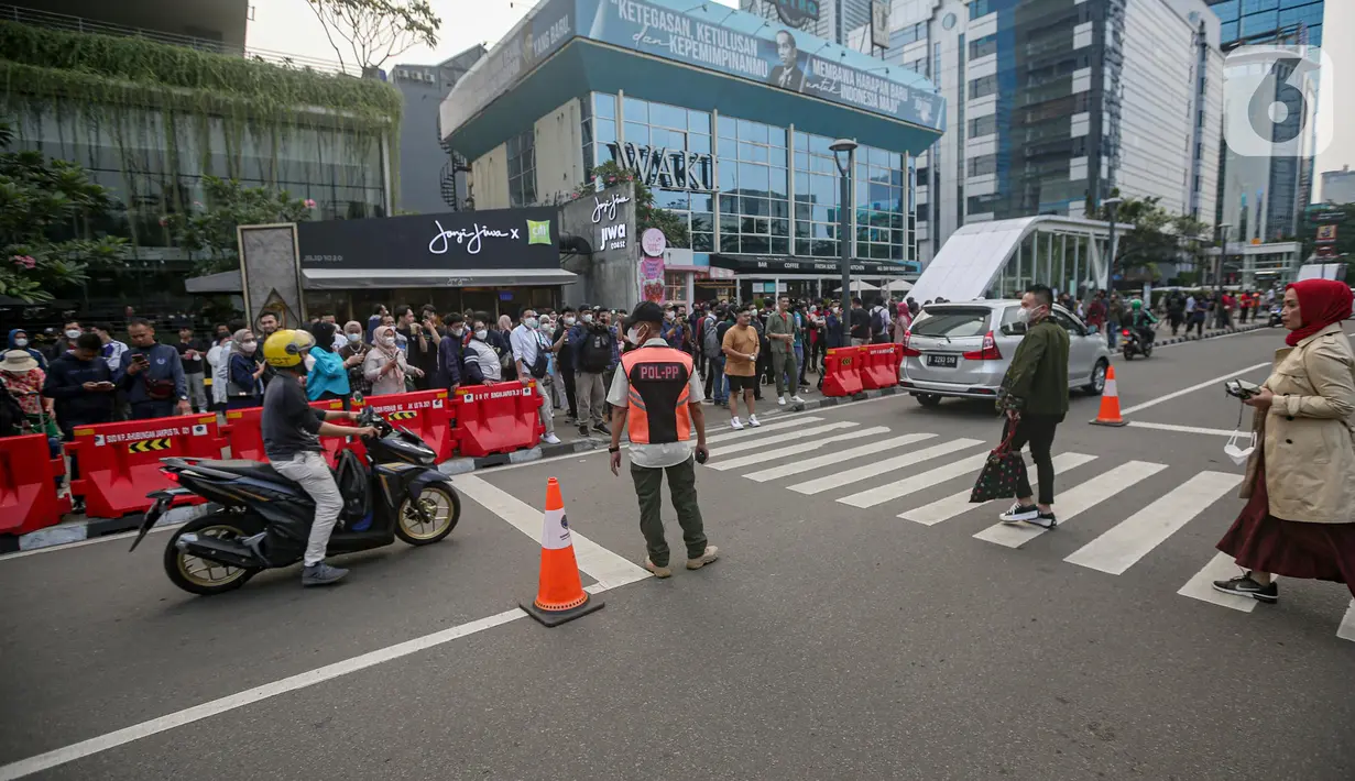 Personel gabungan dari unsur polisi hingga Satpol PP mengatur lalu lintas di kawasan zebra cross Dukuh Atas, Jakarta, Rabu (27/7/2022). Mereka dikerahkan untuk memantau kegiatan peragaan busana Citayam Fashion Week (CFW) guna meminimalisir terjadinya kriminalitas, kemacetan, hingga parkir liar. (Liputan6.com/Faizal Fanani)