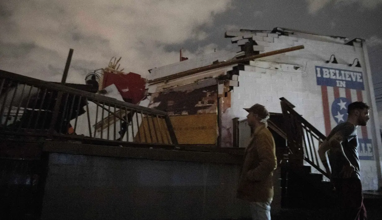 Orang-orang berdiri di luar venue musik Basement East di East Nashville setelah dihantam oleh angin topan, Selasa (3/3/2020). Tornado dekat pusat kota dilaporkan bergerak ke Hermitage, sekitar 16 kilometer timur kota. (Courtney Pedroza / The Tennessean via AP)