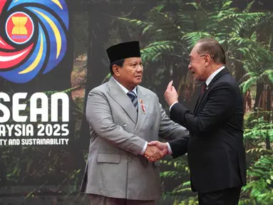 Presiden Republik Indonesia, Prabowo Subianto (kiri) disambut Perdana Menteri Malaysia Anwar Ibrahim saat tiba untuk menghadiri Konferensi Tingkat Tinggi (KTT) ke-47 negara-negara Asia Tenggara (ASEAN) di Kuala Lumpur pada 26 Oktober 2025. (Rafiq Maqbool/POOL/AFP)