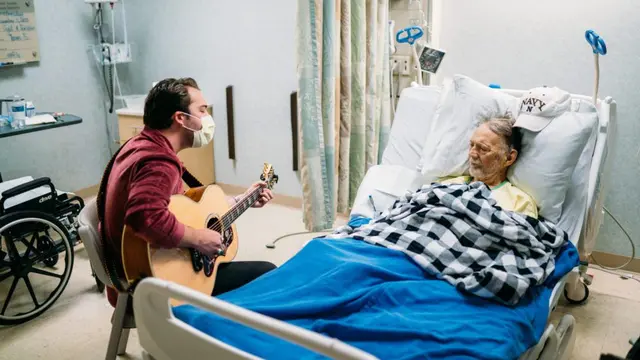 Seorang Musisi yang Bekerja Sama Dengan Musicians On Call Sedang Menghibur Seorang Pasien di Rumah Sakit.