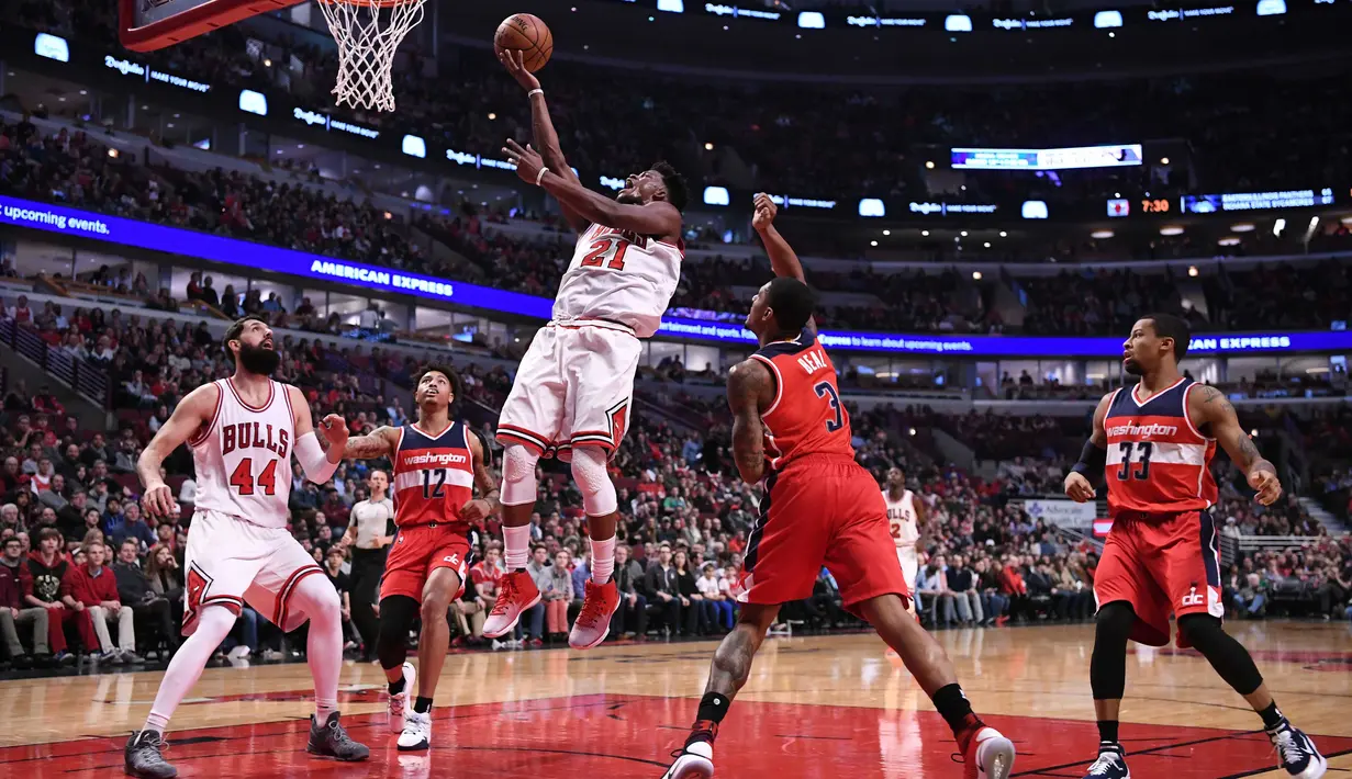 Pemain Chicago Bulls, Jimmy Butler  melakukan layup melewati hadangan para pemain Washington Wizards  pada laga NBA basketball game di United Center, Chicago, (21/12/2016).  Wizards menang 107-97. (Reuters/Mike DiNovo-USA TODAY Sports)