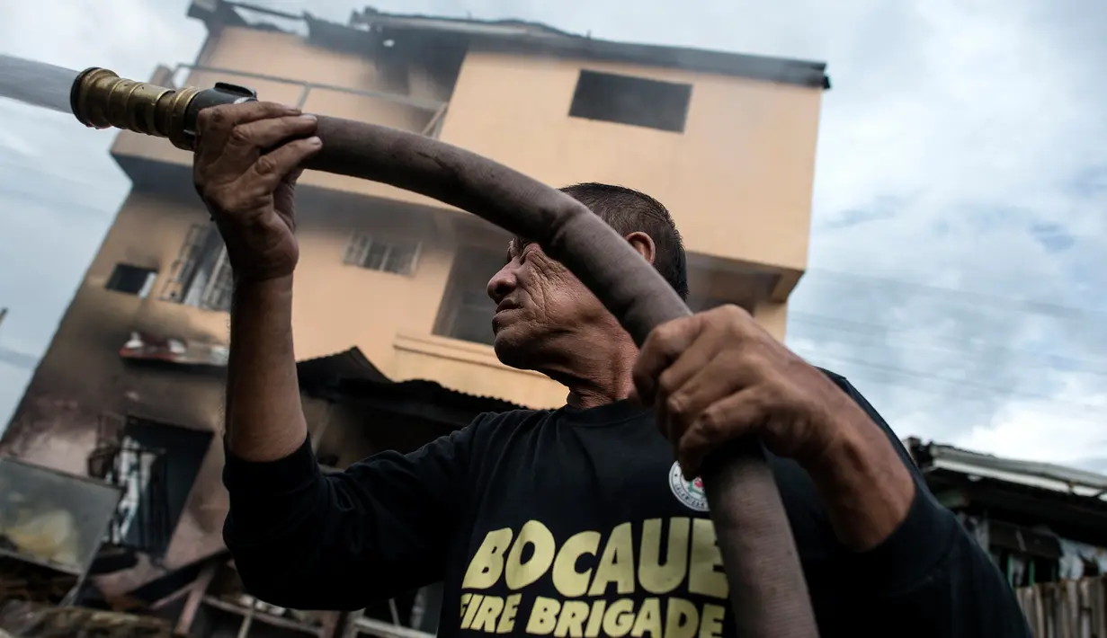 Petugas damkar memadamkan bara api yang masih tersisa di puing salah toko kembang api di Bocaue, 30 km dari Ibu Kota Filipina, Rabu (12/10). Api mendadak merambat ke beberapa toko yang menjual kembang api dan memicu rangkaian ledakan. (Noel Celis/AFP)