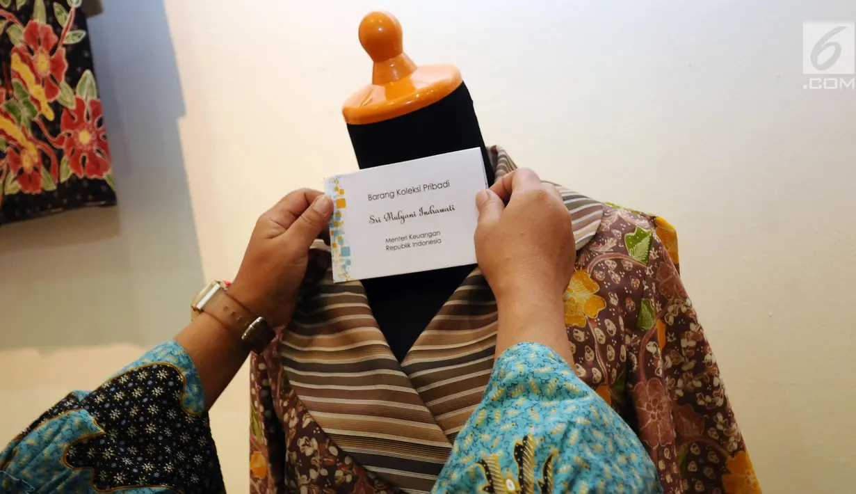 Petugas memasang tulisan di baju batik milik Sri Mulyani yang akan dilelang pada lelang sukarela di Galeri Nasional, Jakarta, Selasa (27/2). Lelang barang pribadi itu merupakan peringatan 110 tahun Lelang Indonesia. (Liputan6.com/Helmi Fithriansyah)