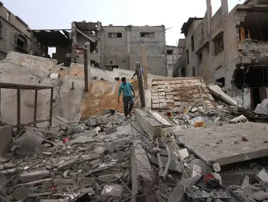 Seorang pria Palestina yang mengungsi berjalan di atas puing-puing setelah pesawat Israel menargetkan sebuah rumah berlantai lima tadi malam, di Khan Yunis, Jalur Gaza selatan pada Kamis 6 Februari 2026. Ketegangan di Jalur Gaza kembali memanas. (Bashar Taleb/AFP)