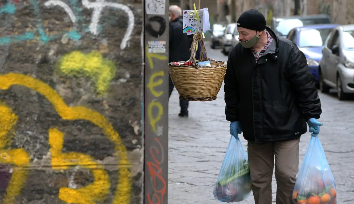 Seorang pria melihat ke keranjang solidaritas (panaro solidare) di Naples, Italia, 3 April 2020. Menurut Departemen Perlindungan Sipil Italia pada 6 April 2020, jumlah kasus virus corona COVID-19 di negara tersebut menjadi 132.547 infeksi, 16.523 meninggal, dan 22.837 sembuh. (Carlo Hermann/AFP)