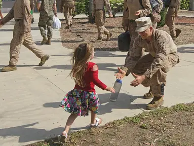 Seorang Angkatan Laut AS menyambut anaknya saat tiba di Camp Pendleton di Oceanside, California, AS, Kamis (11/5). (AFP/ Sandy Huffaker)