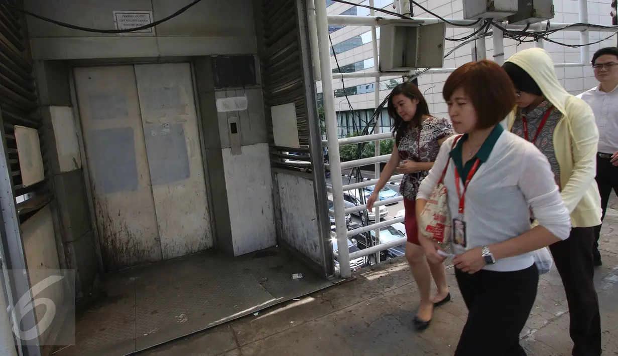 Warga melintas di depan lift khusus lansia dan ibu hamil yang rusak di JPO Sarinah, Jakarta, Kamis (2/3). Kurangnya perhatian pihak terkait menyebabkan lift tersebut menjadi terbengkalai serta tidak berguna. (Liputan6.com/Immanuel Antonius)