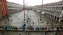 Warga berjalan di Alun-Alun Santo Markus yang banjir akibat terjangan gelombang pasang di Venesia, Italia, Selasa (12/11/2019). Venesia dilanda banjir akibat gelombang pasang setinggi 127 cm. (AP Photo/Luca Bruno)