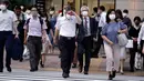Orang-orang mengenakan masker mencegah penyebaran coronavirus baru berjalan di atas penyeberangan pejalan kaki di Tokyo, Senin, (20/7/2020). Ibukota Jepang hari Senin mengkonfirmasi lebih dari 160 kasus virus corona baru. (AP Photo/Eugene Hoshiko)