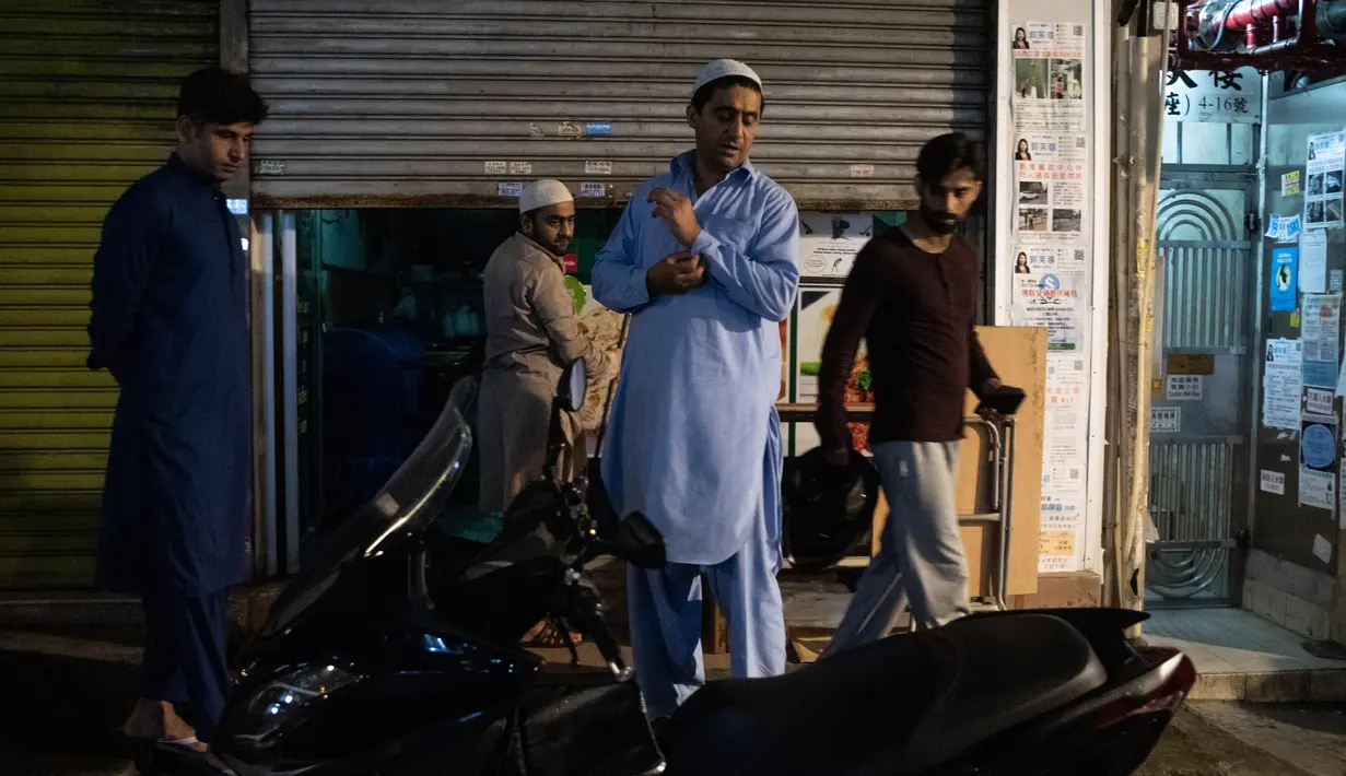 Para imigran Pakistan berkumpul untuk melakukan salat subuh usai menyantap sahur di distrik Kwai Chung, Hong Kong (25/5/2019). Kwai Chung adalah daerah perkotaan di dalam Kota Baru Tsuen Wan di Wilayah Baru Hong Kong. (AFP Photo/Philip Fong)