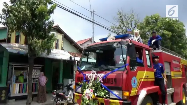 Sepasang pengantin diarak menggunakan mobil pemadam kebakaran setelah selesai melaksanakan ijab qabul. Kejadian unik ini menarik perhatian warga sekitar.