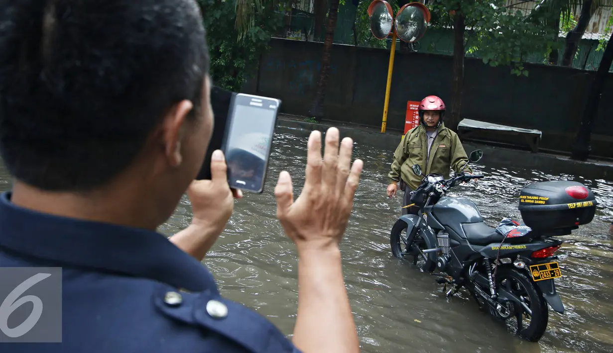 Warga berpose disamping motor saat banjir menggenangi kawasan Sunter, Jakarta, Kamis (25/2). Hujan deras yang mengguyur Jakarta serta sistem drainase yang buruk menjadi penyebab banjir sehingga mengganggu aktivitas warga. (Liputan6.com/Immanuel Antonius)