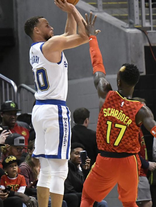 Aksi pemain Warriors, Stephen Curry melakukan tembakan melewati adangan pemain Atlanta Hawks, Dennis Schroder pada laga NBA basketball game  di Philips Arena, Atlanta, (2/3/2018). Warriors menang 114-109. (AP/John Amis)