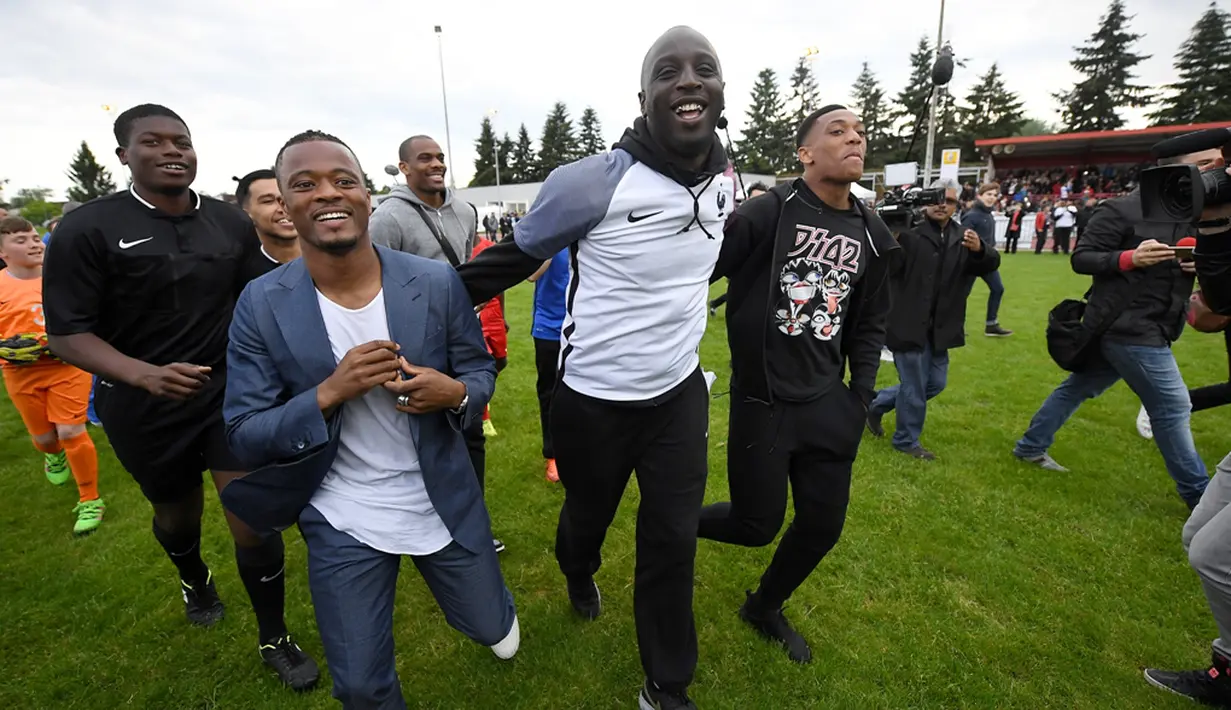 Pemain Timnas Prancis, Patrice Evra dan Anthony Martial, saat hadir dan berbagi pengalaman kepada para pemain muda Les Ulis di lapangan latihan Les Ulis, (23/5/2016). (AFP/Franck Fife)