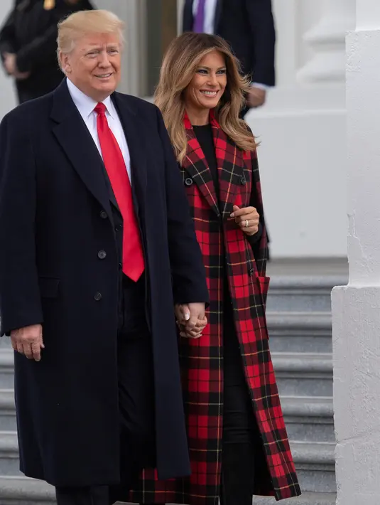 Presiden Donald Trump bersama First Lady AS, Melania Trump menyambut kedatangan pohon Natal resmi Gedung Putih di halaman Utara Gedung Putih, Washington, Senin (19/11). Pohon Natal tersebut diantar dengan kereta kuda. (Jim WATSON / AFP)