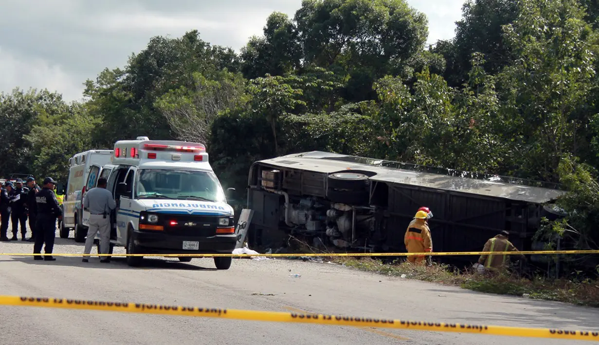 Mobil ambulans terparkir dekat bus wisata yang terbalik di Quintana Roo, Meksiko, Selasa (19/12). Bus sedang membawa 31 wisatawan saat kehilangan kendali dan terguling di situs bersejarah di Semenanjung Yucatan itu. (Novedades de Quintana Roo via AP)