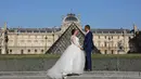 Sepasang calon pengantin melakukan foto prewedding dengan latar belakang Pyramide de Louvre di Paris, 9 Juli 2017. Bukan cuma menara Eiffel yang sudah amat terkenal itu, ibukota Perancis ini juga punya Piramida Louvre. (AFP PHOTO / LUDOVIC MARIN)