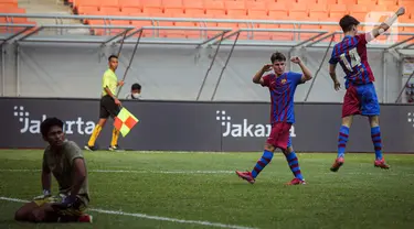 Pemain Barcelona U-18 Jan Molina Vilaseca (kanan) melakukan selebrasi usai mencetak gol ke gawang Bali United U-18 pada pertandingan International Youth Championship (IYC) 2021 di Jakarta International Stadium (JIS), Jakarta, Minggu (17/4/2022). Barcelona U-18 menang 3-0.(Liputan6.com/Faizal Fanani)