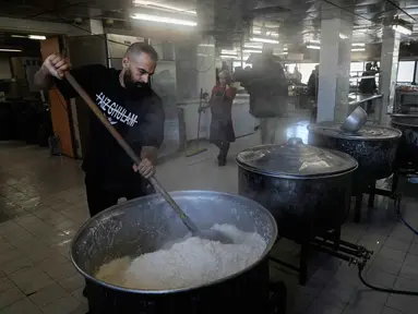 Para sukarelawan memasak makanan untuk para pengungsi yang menghindari serangan udara Israel di Lebanon selatan dan Dahiyeh, di Institut Teknik Bir Hassan yang telah diubah menjadi tempat penampungan, Beirut, Rabu 11 Maret 2026. Ratusan ribu warga Lebanon terpaksa mengungsi dari pinggiran selatan Beirut setelah peringatan evakuasi dan serangan udara Israel. (AP Photo/Bilal Hussein)