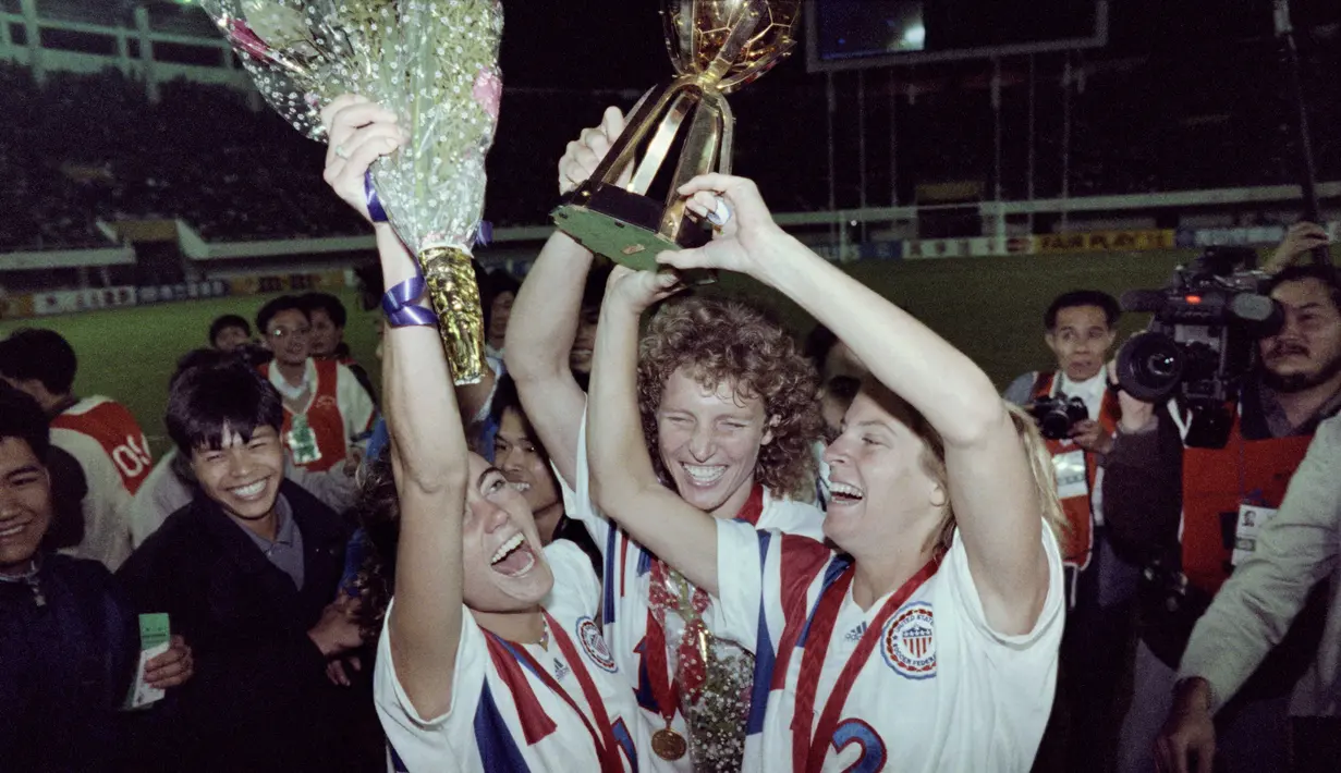 Carin Jennings (kanan) mengangkat trofi juara setelah Amerika Serikat mengalahkan Norwegia dengan skor 2-1 pada Piala Dunia Wanita pertama tahun 1991 di China. ( AFP/Tommy Cheng )