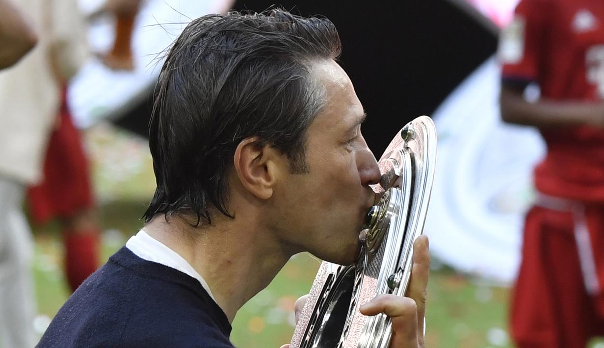 Pelatih Bayern Munchen, Niko Kovac, mencium trofi Bundesliga usai mengalahkan Frankfurt di Allianz Arena, Jerman, Sabtu (18/5). Munchen menang 5-1 atas Frankfurt. (John Macdougall/AFP)