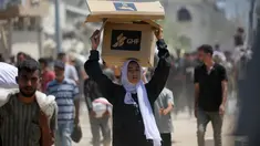 Seorang wanita Palestina membawa bantuan makanan ketika orang-orang kembali ke kamp pengungsi Nuseirat dari titik distribusi Yayasan Kemanusiaan Gaza yang didukung oleh Amerika Serikat (AS) di dekat koridor Netsarim, Jalur Gaza tengah, pada 27 Juli 2025. (Eyad BABA/AFP)