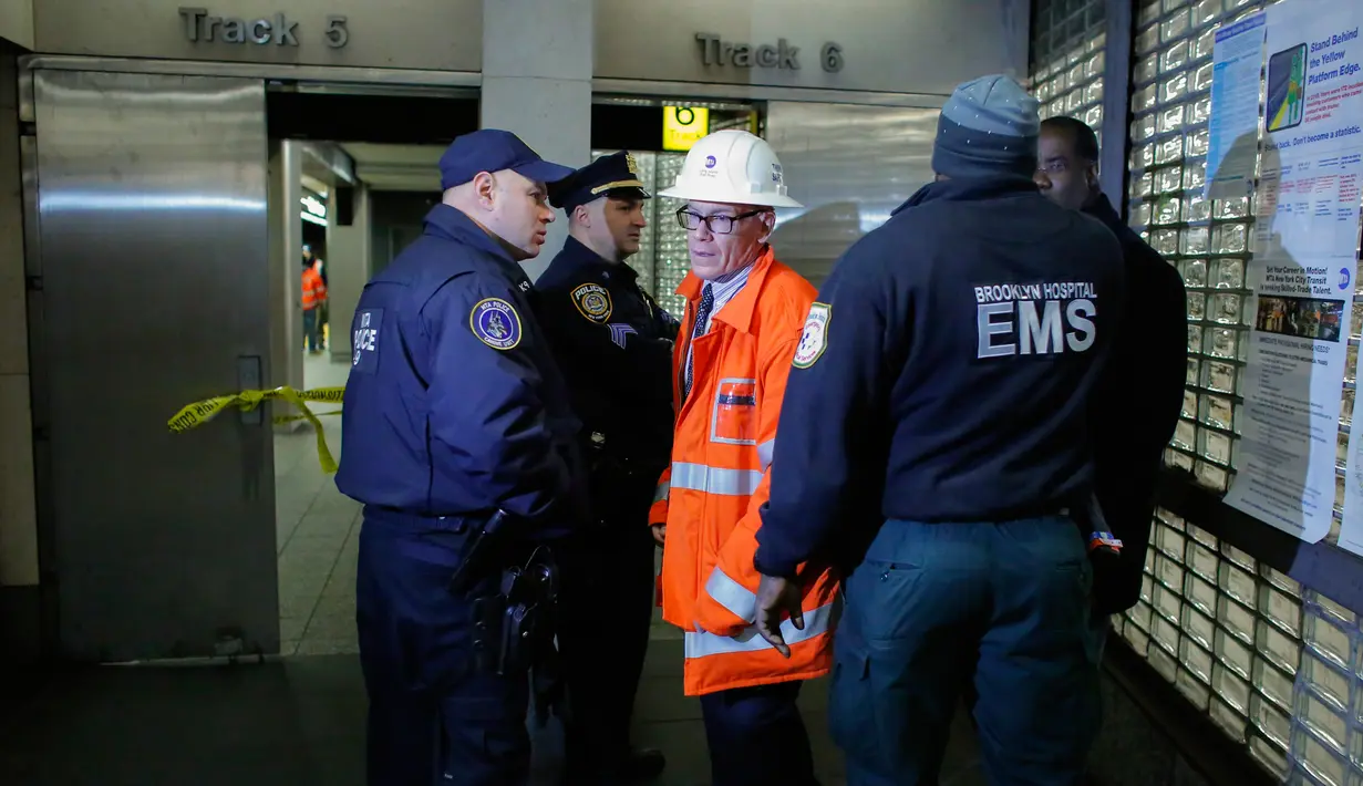 Petugas kepolisian dan pemadam kebakaran mendatangi lokasi tergelincirnya satu rangkaian kereta komuter Long Island Rail Road (LIRR) di Brooklyn Atlantic Terminal, New York, Rabu (4/1). Insiden itu melukai lebih dari 100 orang. (AFP PHOTO/Kena Betancur)