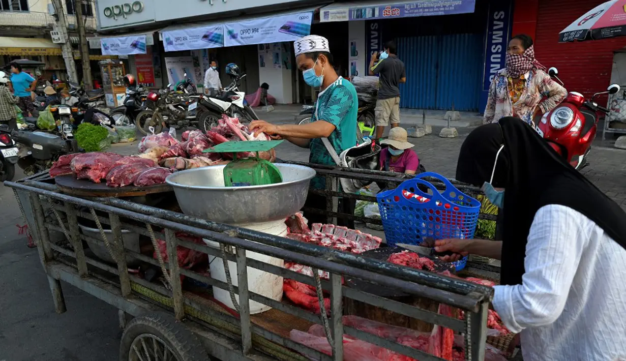 Pedagang menyiapkan daging untuk dijual di sepanjang jalan karena pasar tetap tutup di tengah pembatasan lockdown yang diberlakukan untuk mencoba menghentikan lonjakan kasus virus corona COVID-19 di Phnom Penh, Kamboja, Selasa (11/5/2021). (TANG CHHIN Sothy/AFP)