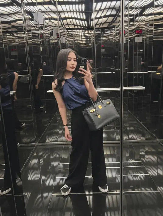Penampilan simple chic Prilly Latuconsina pakai atasan blouse tanpa lengan halter-neck berwarna biru yang dipadunya dengan celana panjang hitam. [Foto: Instagram/prillylatuconsina96]