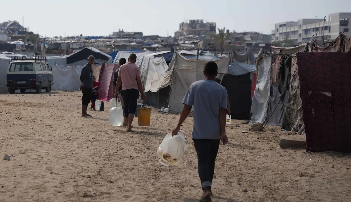 Warga hanya mendapatkan 6 hingga 7 liter air per hari, jauh di bawah standar kemanusiaan. Tampak dalam foto, para pengungsi Palestina membawa jerigen berisi air melalui kamp tenda di Khan Younis, Jalur Gaza Selatan, Kamis 30 April 2026. (AP Photo/Abdel Kareem Hana)