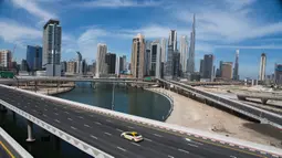 Sebuah taksi melintasi jalan raya yang sepi dekat Burj Khalifa di Dubai, Uni Emirat Arab, Senin (6/4/2020). Pemerintah Dubai memberlakukan lockdown selama dua pekan untuk mengantisipasi penyebaran virus corona COVID-19. (AP Photo/Jon Gambrell)
