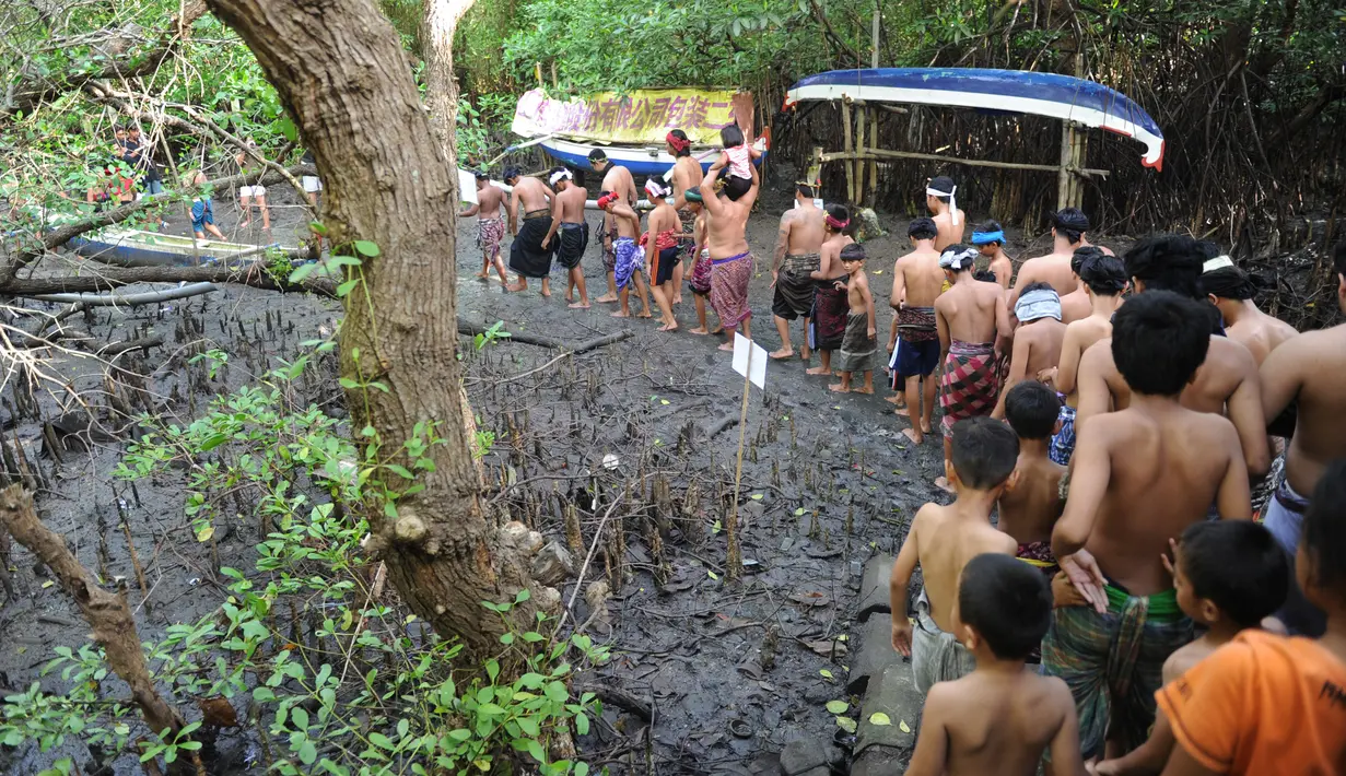 Warga Bali berjalan bersama menuju hutan manggrove untuk mandi lumpur tradisional atau yang dikenal sebagai Mebuug-buugan di desa Kedonganan, Bali (18/3). (AFP/Sony Tumbelaka)