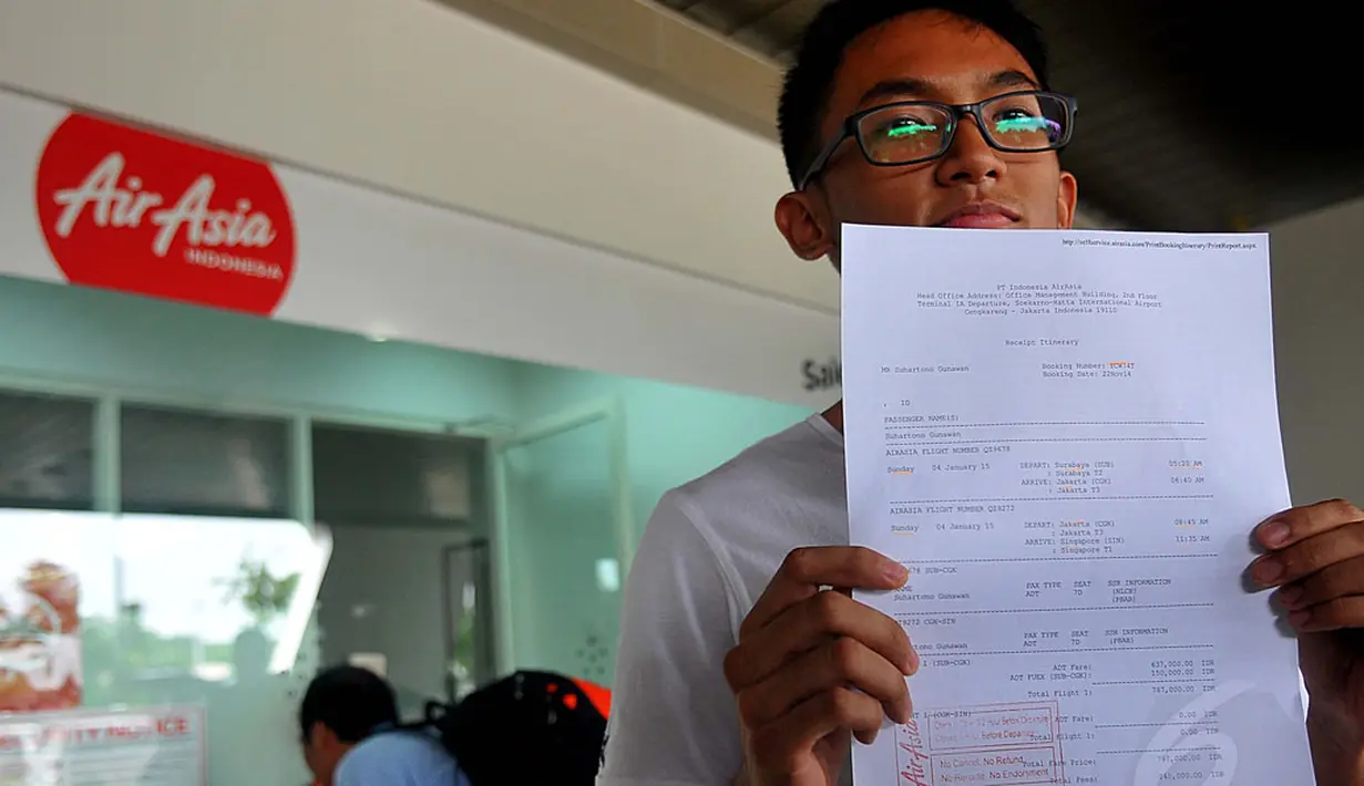 Calon penumpang pesawat AirAsia, Hartono Gunawan menunjukan tiket perubahan jadwal penerbangan Surabaya-Singapura di Terminal 2 Bandara Juanda, Surabaya, Sabtu (3/1/2015). (Liputan6.com/Johan Tallo)