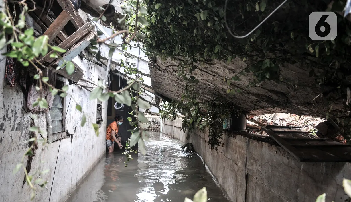 Warga membersihkan sampah di rumahnya yang rusak akibat derasnya arus banjir di kawasan Kemang Timur XI, Jakarta Selatan, Minggu (21/2/2021). Longsor terjadi akibat derasnya arus kali yang kemudian bangunan menimpa permukiman warga di bawahnya. (merdeka.com/Iqbal S. Nugroho)