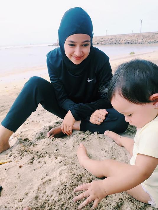 Sebagai seorang ibu, Aryani juga memboyong si kecil bernama Alem Isco saat traveling ke pantai. Potret mesra ibu dan anak terlihat jelas saat keduanya bermain pasir pantai secara bersamaan. (Liputan6.com/IG/@aryanifitriana24)