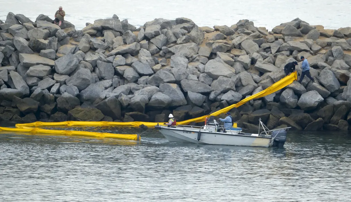 Sebuah kapal menyebarkan penghalang setelah tumpahan minyak di Pantai Newport, California, Amerika Serikat, 4 Oktober 2021. Tumpahan minyak menyebabkan ikan dan burung mati berserakan. (AP Photo/Ringo H.W. Chiu)