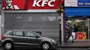 Pejalan kaki melewati sebuah gerai makanan cepat saji KFC yang tutup sementara di London, Inggris, Senin (19/2). Krisis pasokan ayam pada KFC diperkirakan akan berlangsung hingga akhir pekan ini. (BEN STANSALL/AFP)