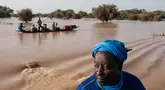 Orang-orang membawa barang-barang di atas kereta dorong di atas air banjir yang mengalir di jalan utama Odobere pada tanggal 22 Oktober 2024. (GUY PETERSON/AFP)