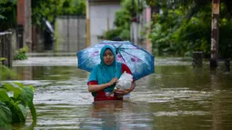 Seorang perempuan melintasi lingkungan yang banjir setelah tiga hari diguyur hujan lebat di Banda Aceh, Aceh, Sabtu (9/5/2020). Banjir akibat intensitas hujan tinggi tersebut mengakibatkan sebagian besar kawasan di ibu kota Provinsi Aceh ini digenangi air. (Photo by CHAIDEER MAHYUDDIN/AFP)