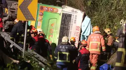 Tim SAR berusaha mengevakuasi bangkai bus pariwisata yang terbalik di ruas jalan dekat Taipe, ibu kota Taiwan, Selasa (14/2). Bus dilaporkan telah berusia 19 tahun dan dimiliki sebuah agen wisata yang melayani tur di seluruh Taiwan. (AP Photo)