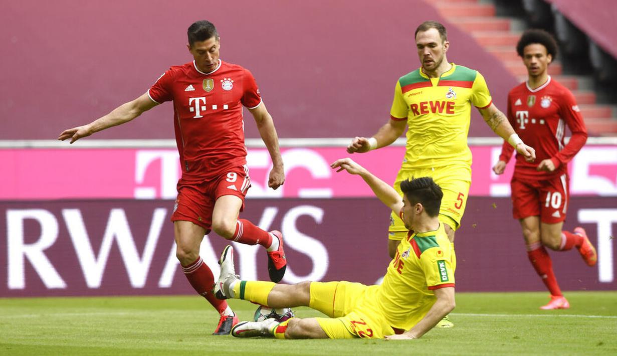 Striker Bayern Munchen, Robert Lewandowski, berusaha melewati pemain FC Koln, Jorge Meré, pada laga Bundesliga di Stadion Allianz, Minggu (27/2/2021). Bayern menang dengan skor 5-1. (AP/Andreas Schaad)