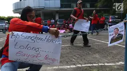 Seorang pria mantan karyawan 7-Eleven memasang poster saat melakukan aksi di Jakarta, Rabu (22/2). Jumlah total pesangon untuk anggota serikat pekerja PT Modern Putra Indonesia itu sebesar Rp 17,5 miliar. (Liputan6.com/Angga Yuniar)