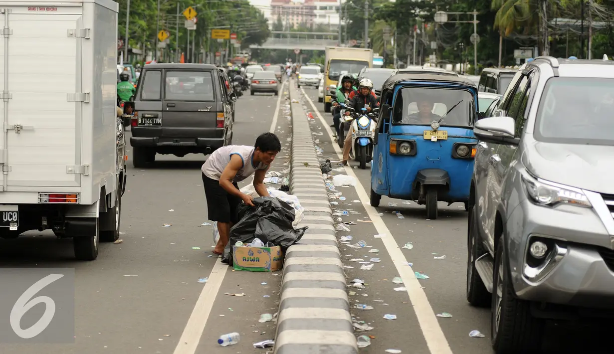 Pemulung memunguti sisa kemasan makanan dan minuman di Jalan Medan Merdeka Timur usai massa ormas melakukan unjuk rasa di Bareskrim Polri, Gedung KKP Jakarta, Jumat (14/10). Dalam aksinya, massa meminta Ahok ditahan. (Liputan6.com/Helmi Fithriansyah)