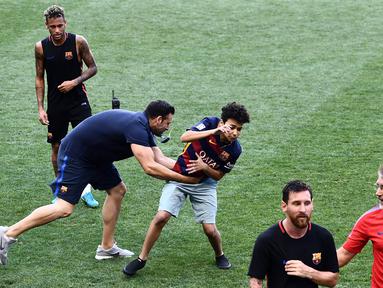 Petugas menangkap fans yang masuk ke lapangan mengejar pemain Barcelona, Lionel Messi dan Neymar saat latihan di Red Bull Arena, New Jersey, Jumat (21/7/2017). Latihan ini dilakukan jelang laga ICC 2017 melawan Juventus. (AFP/Jewel Samad)
