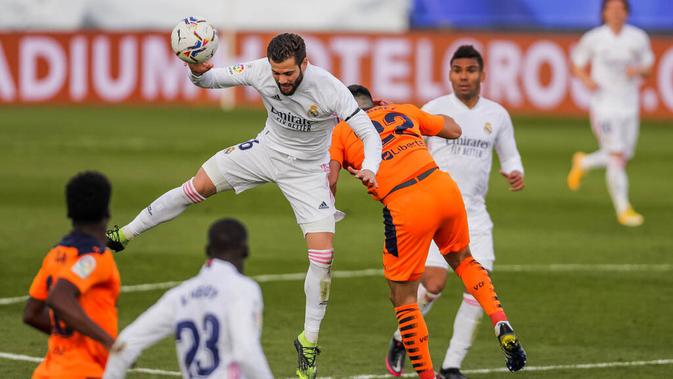 Pemain Real Madrid, Nacho, berebut bola dengan pemain Valencia, Maxi Gomez, pada laga Liga Spanyol di Stadion Alfredo Di Stefano, Minggu (14/2/2021). Real Madrid menang dengan skor 2-0. (AP/Manu Fernandez)