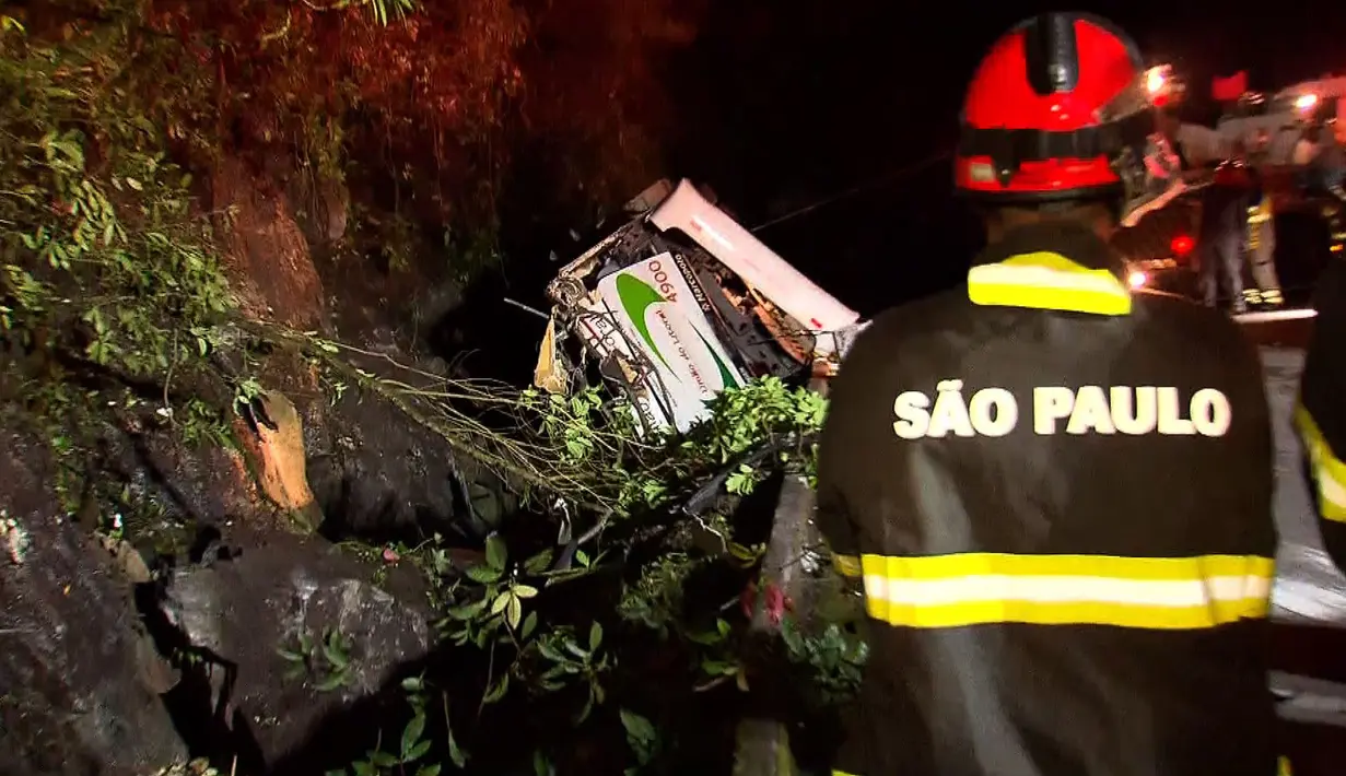 Petugas pemadam kebakaran dikerahkan di lokasi kecelakaan bus yang hilang kendali dan terjun bebas ke jurang di negara bagian Sao Paulo, Brasil, Kamis (9/6). Menurut laporan media lokal, sopir bus termasuk dalam deretan korban tewas. (RECORD TV/AFP)